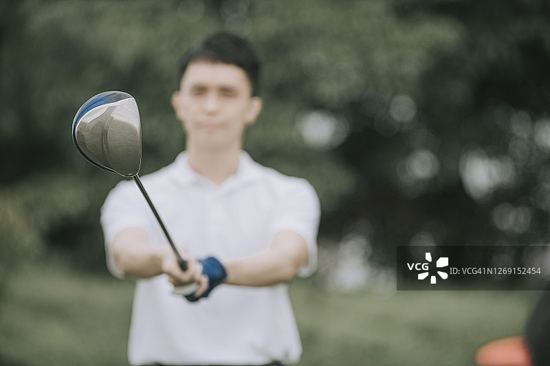 亚洲华人男子在雨中打高尔夫球，在马六甲独自湿开球挥杆图片素材