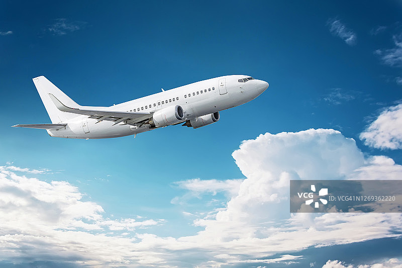 民航飞机飞进了有云的深蓝色天空图片素材