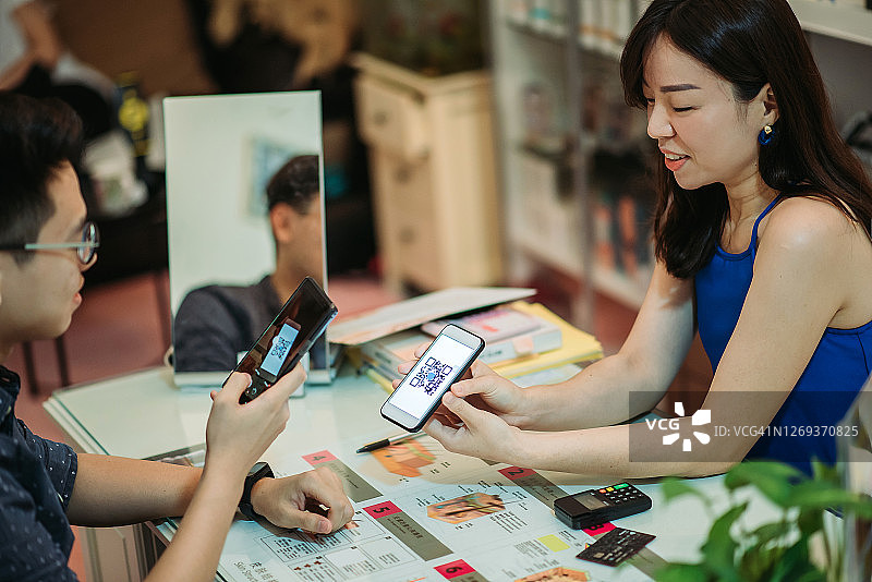 亚洲华人美女在美容院用手机扫描条形码接受非接触式支付图片素材