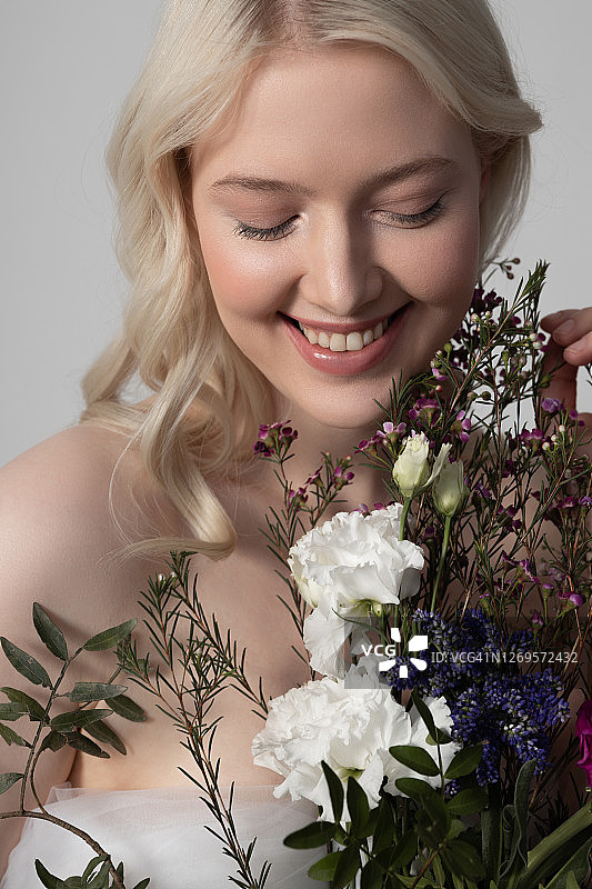 快乐的年轻女子与完美的皮肤拿着美丽的鲜花图片素材