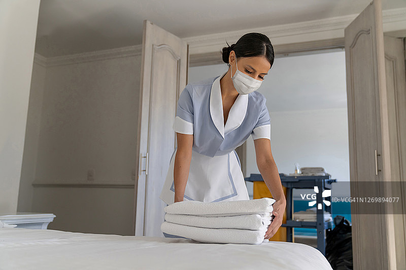 酒店服务员戴着口罩整理床铺图片素材