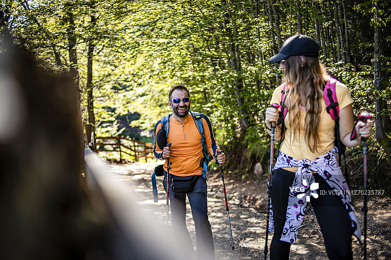 两个年轻的登山者出发去征服山顶-幸福的夫妇一起徒步旅行在山与背包-男人和女人游客步行在山图片素材