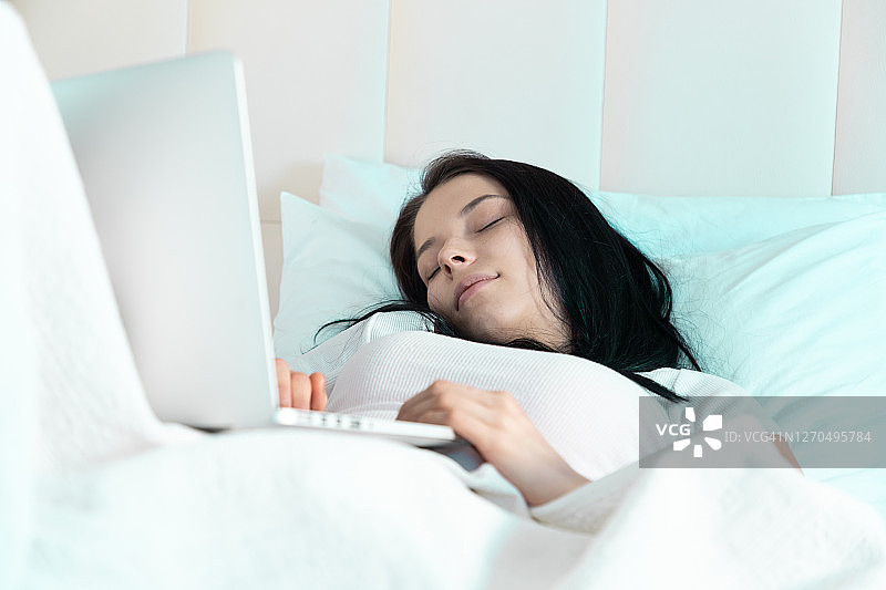 年轻女性在使用笔记本电脑时睡着了图片素材