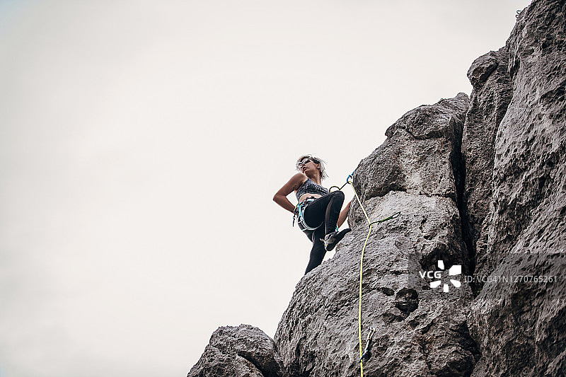 年轻女子攀登者在大自然的岩石上爬得很高图片素材