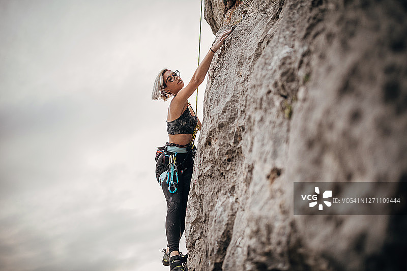 年轻女性自由攀登者在岩石上攀爬图片素材