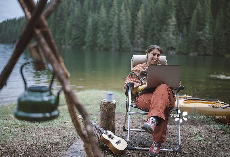 年轻美丽的女人是有乐趣在她的假期在山里工作在她的笔记本电脑图片素材