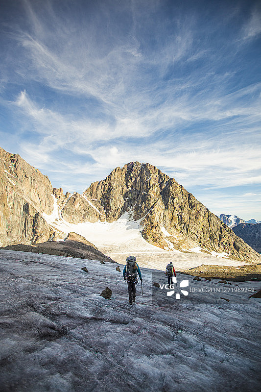 两个人穿过高山的关口穿过冰川。图片素材