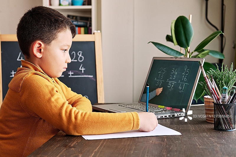 6-7岁可爱的孩子从电脑学习数学。学习在家里。图片素材