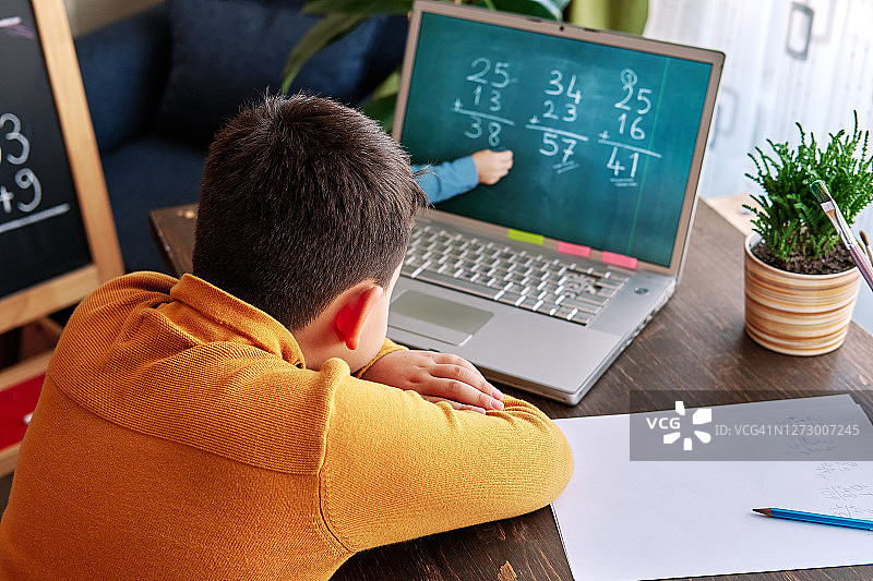 6-7岁可爱的孩子从电脑学习数学。学习在家里。图片素材