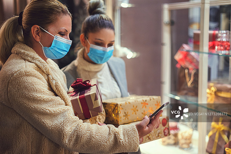 2019冠状病毒病大流行期间，家庭购买圣诞礼物。他们戴着防护口罩，以防止冠状病毒感染。图片素材