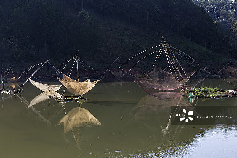 孤独的渔民在湖边的渔场收获，神奇的渔网和独特的日出风景如童话般图片素材