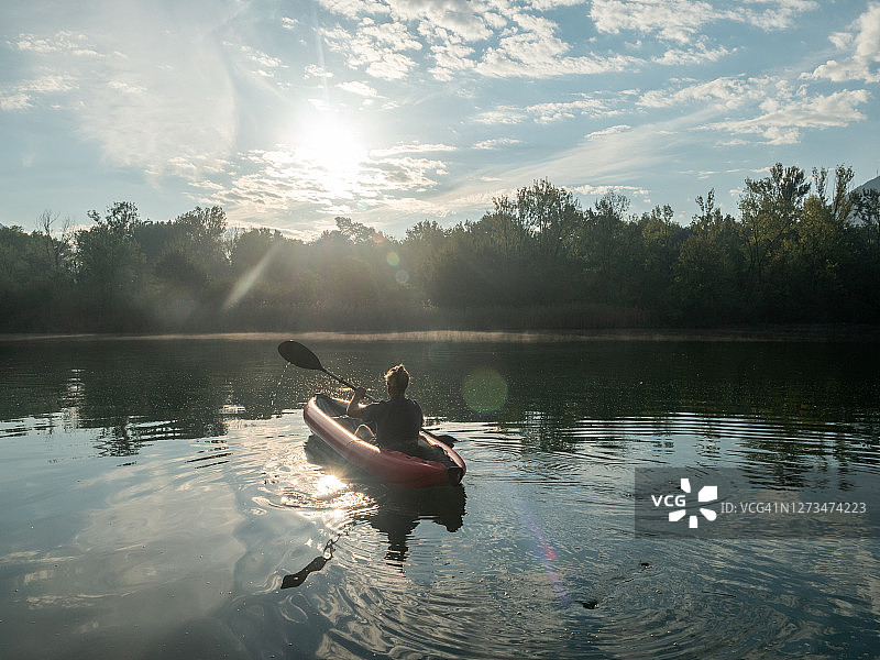 日出时在河上划独木舟的人图片素材