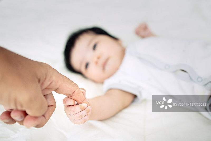 新生儿握着父母的手。图片素材