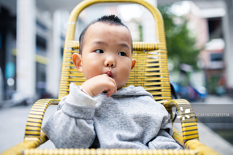 亚洲小男孩坐在婴儿车里吮手指图片素材
