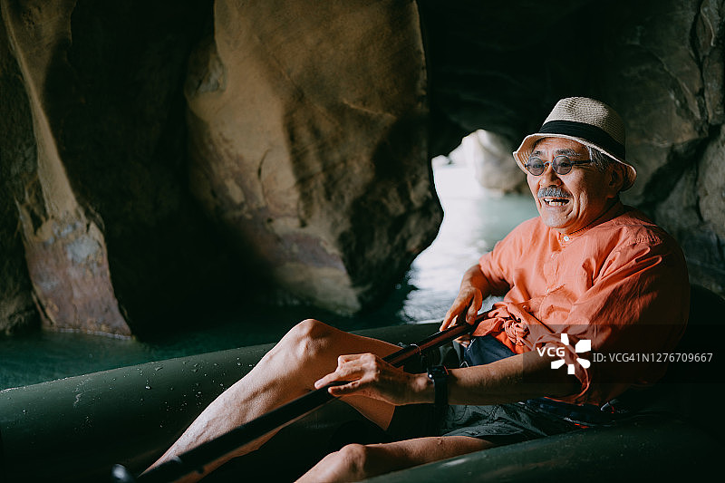 日本种子岛，老人划着小舟穿过山洞图片素材