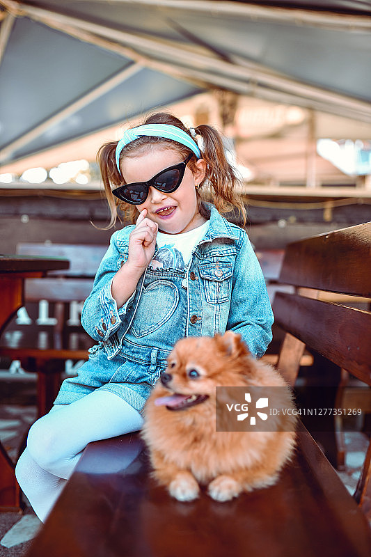 小女孩和博美犬坐在长椅上图片素材