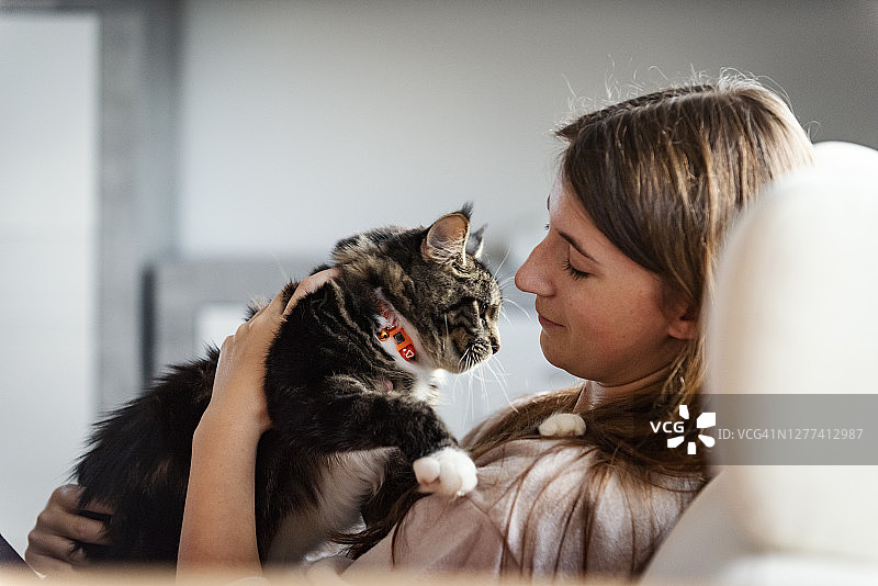 年轻女子与她的猫在家放松图片素材