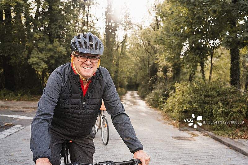 成熟的男子骑自行车戴头盔和休闲运动服图片素材