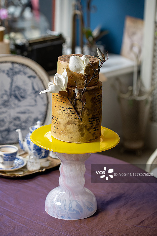 漂亮的3层婚礼蛋糕装饰鲜花在桌子上。黄色和粉红色的蛋糕架。图片素材