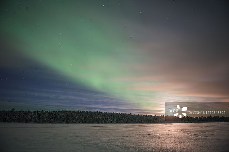 北极光，北极光和月亮，在芬兰拉普兰的一个冰雪覆盖的湖面上，在芬兰的北极圈内图片素材