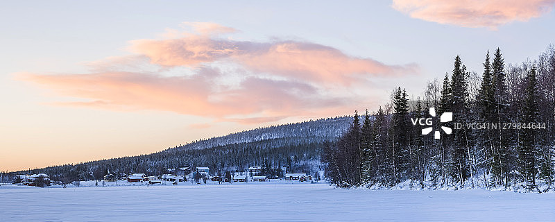 在芬兰拉普兰的北极圈内，阿卡斯隆波罗镇上空戏剧性的天空和日落的云朵，冰冻的湖泊和树木图片素材