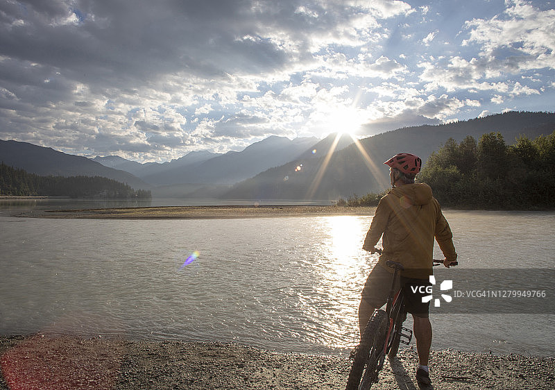 骑山地车的人在日出时在湖边休息图片素材