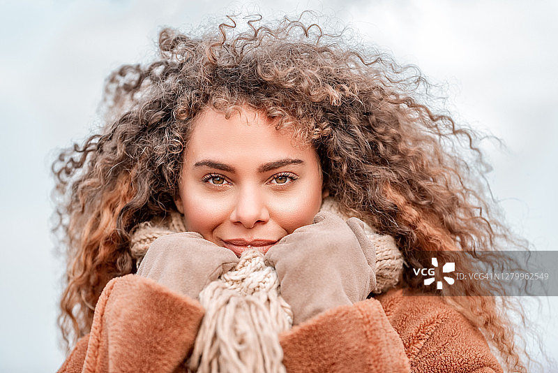 一个美丽的年轻女子的肖像与大卷曲的头发在冬天图片素材