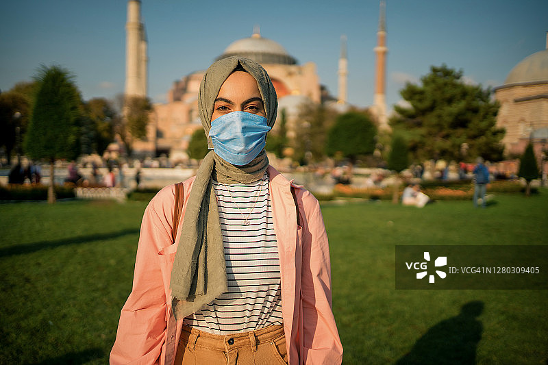由于冠状病毒，一名妇女戴着医用口罩在圣索菲亚大教堂前摆姿势图片素材