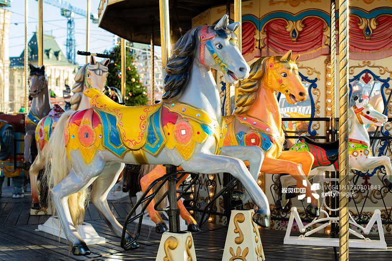彩色马的节日旋转木马特写。一个好玩的骑马儿童，一个灰色的玩具马有一个马鞍图片素材