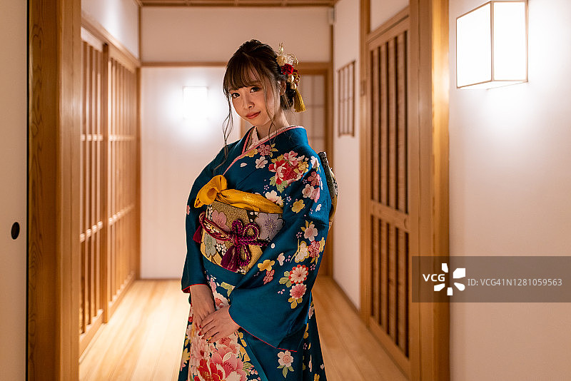 身着Furisode和服的年轻女子站在日本旅馆的走廊上图片素材