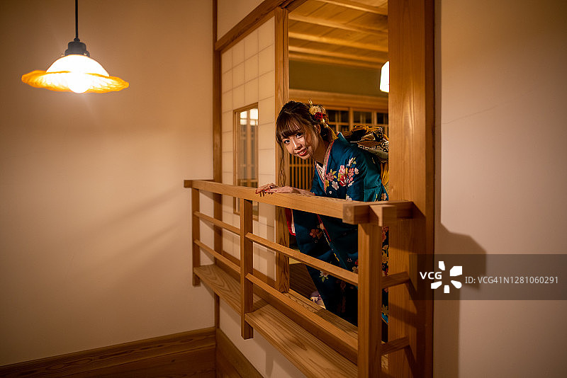 穿着furisode和服的年轻女子从日式旅馆的榻榻米房间看风景图片素材