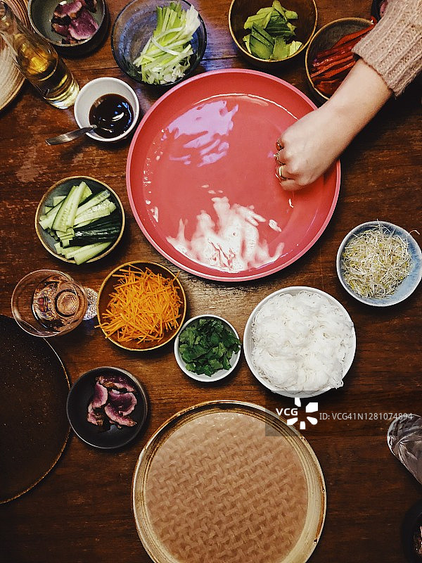 用亚洲食物装饰的桌子。一家人吃春卷的全景。图片素材