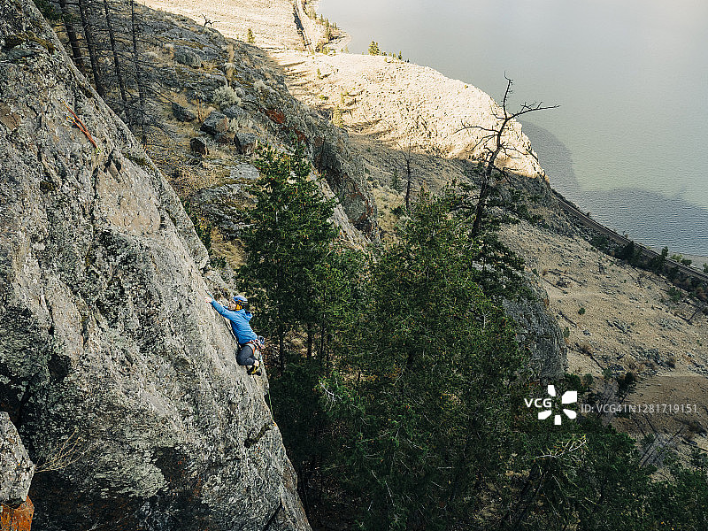 男性攀岩者在一天的晚些时候攀登一个湖上的高运动攀岩图片素材