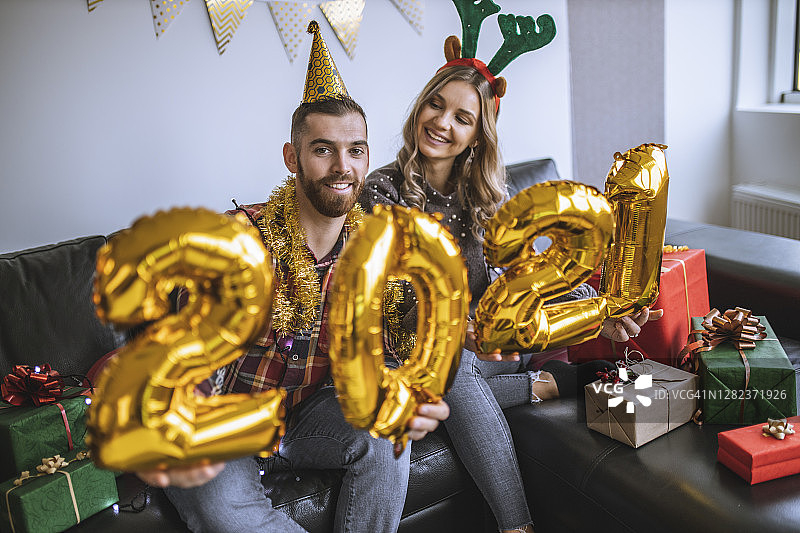 年轻的朋友们在新年派对上玩得很开心，拿着气球上写着“2021”，代表即将到来的新年图片素材