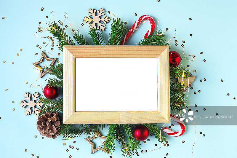 空白的白色木制画框与复制空间。圣诞节天然松树或冷杉树枝为背景。圣诞彩灯，松果和植物天然装饰。图片素材
