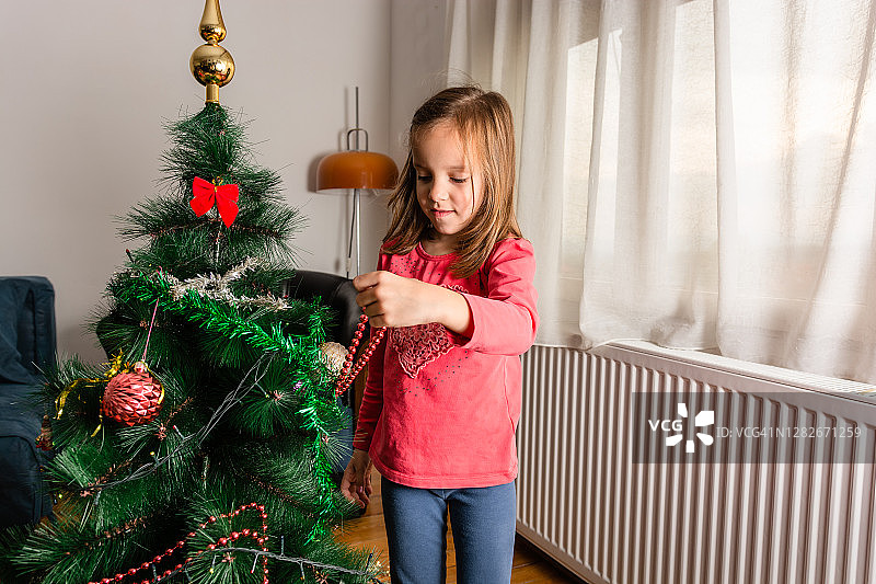 可爱的小女孩装饰圣诞树图片素材
