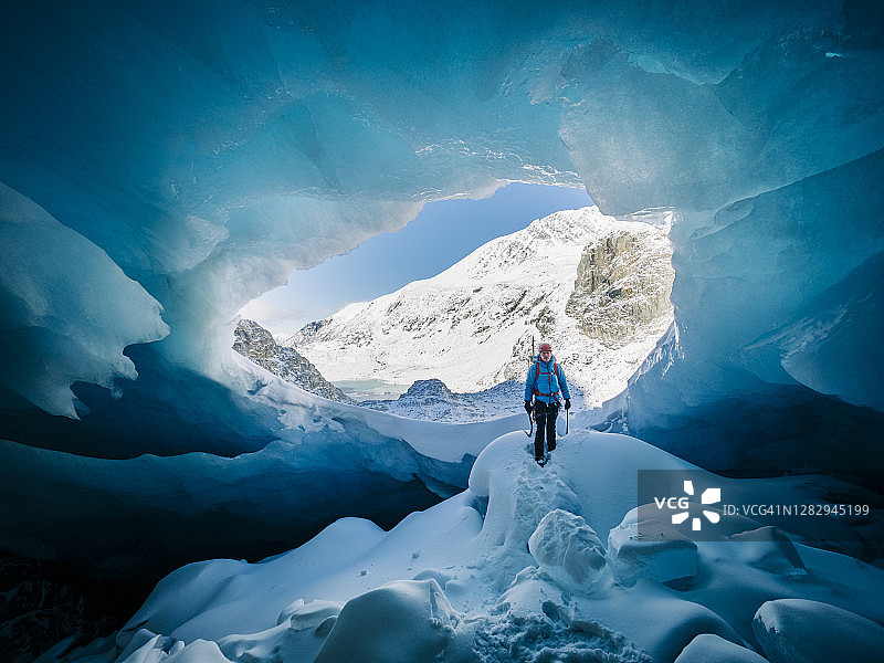 一只雄性攀冰者站在通往一个大冰洞的沟里图片素材