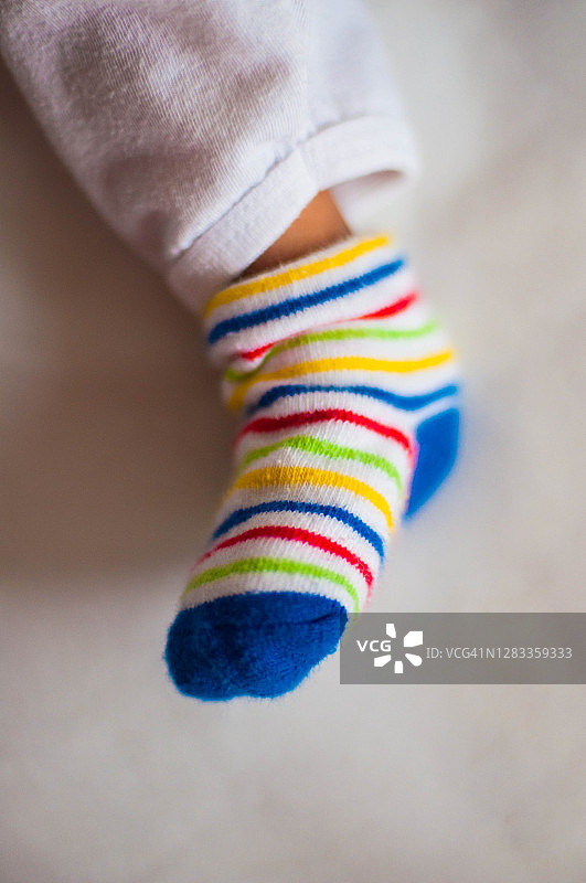 新生婴儿躺在床上，穿着鲜艳的彩色袜子图片素材