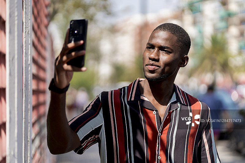 年轻人在城市里用智能手机自拍图片素材