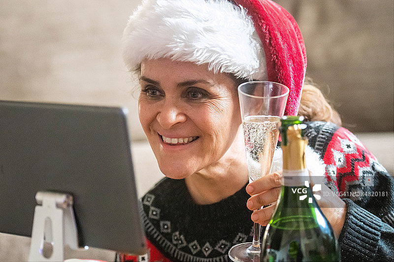 微笑成熟的女人用一杯香槟向一个电话会议的朋友敬酒图片素材