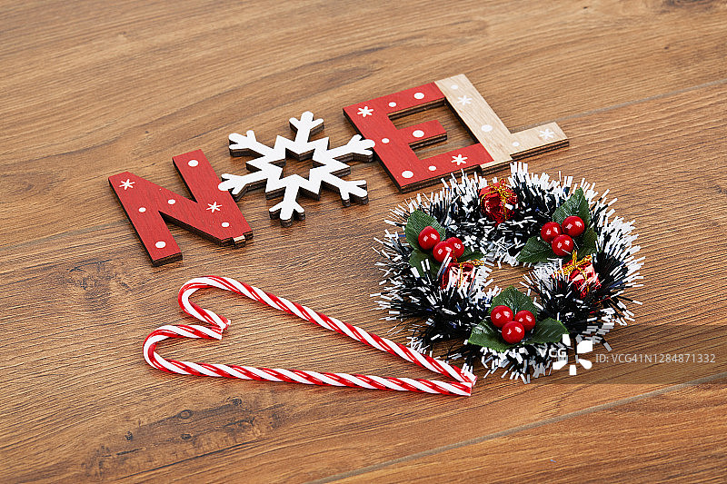 圣诞花环和糖果拐杖与诺埃尔字标志在一个木制背景图片素材