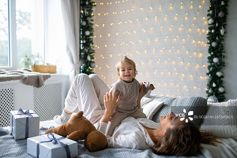 在圣诞节的早晨，年轻的母亲和她的女儿玩得很开心。图片素材