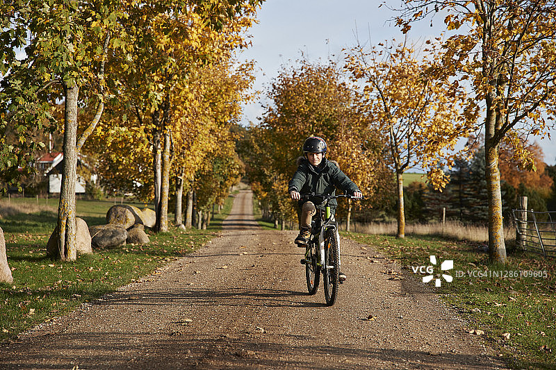 男孩骑着自行车在乡间的砾石路上图片素材