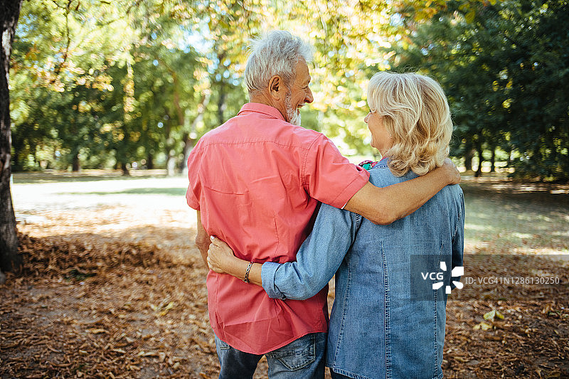 拥抱在公园散步的老夫妇图片素材