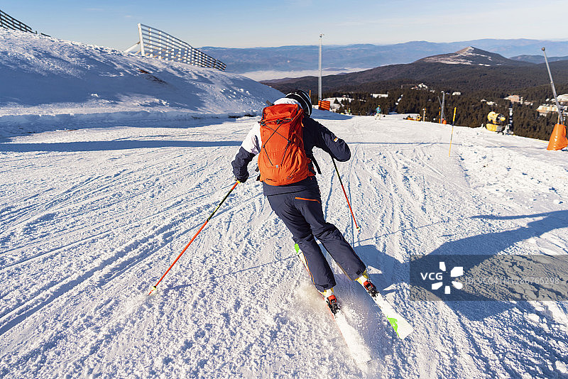 一个男性滑雪者滑雪下山的后视图图片素材