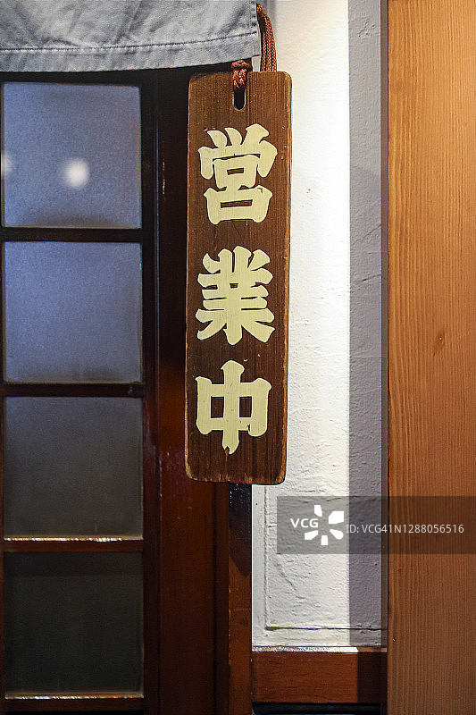 日本人晚上在一家餐馆门口挂着开门的牌子图片素材