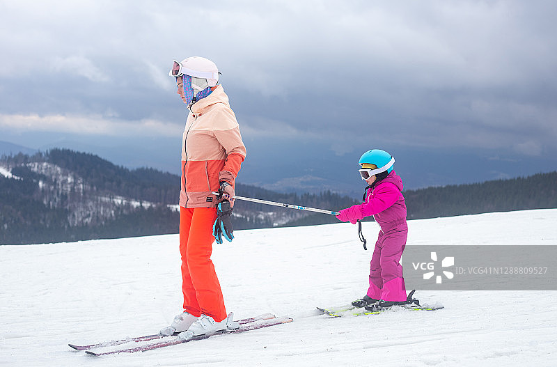 那孩子正和他母亲一起滑雪。图片素材