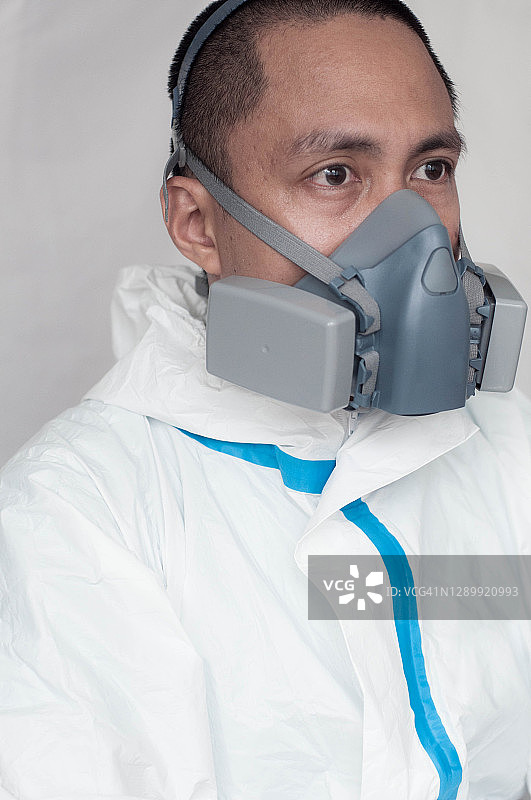 疲惫不堪的东南亚男医生戴着防护口罩和防护服图片素材