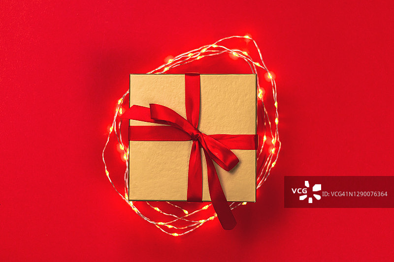 金色圣诞礼物与仙女灯在红色的背景。图片素材