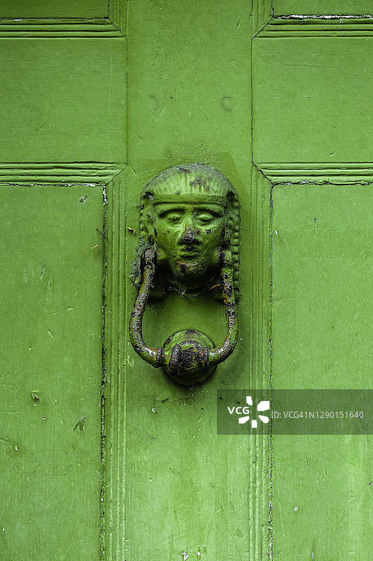 一个绿色门上的老斯芬克斯头门环的特写图片素材